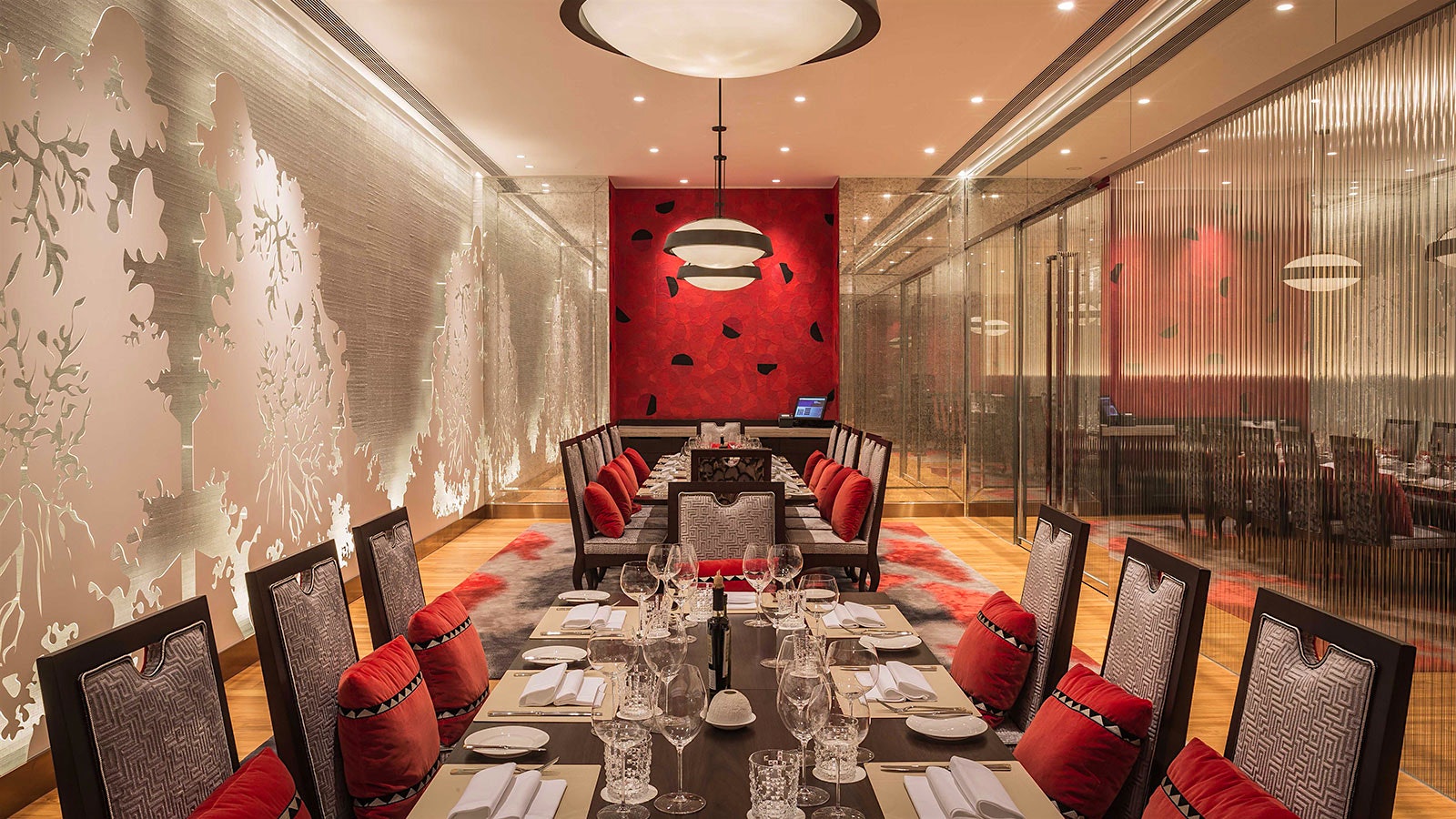A modernist private dining room at Casa Don Alfonso, with patterned chairs, red pillows and a red accent wall